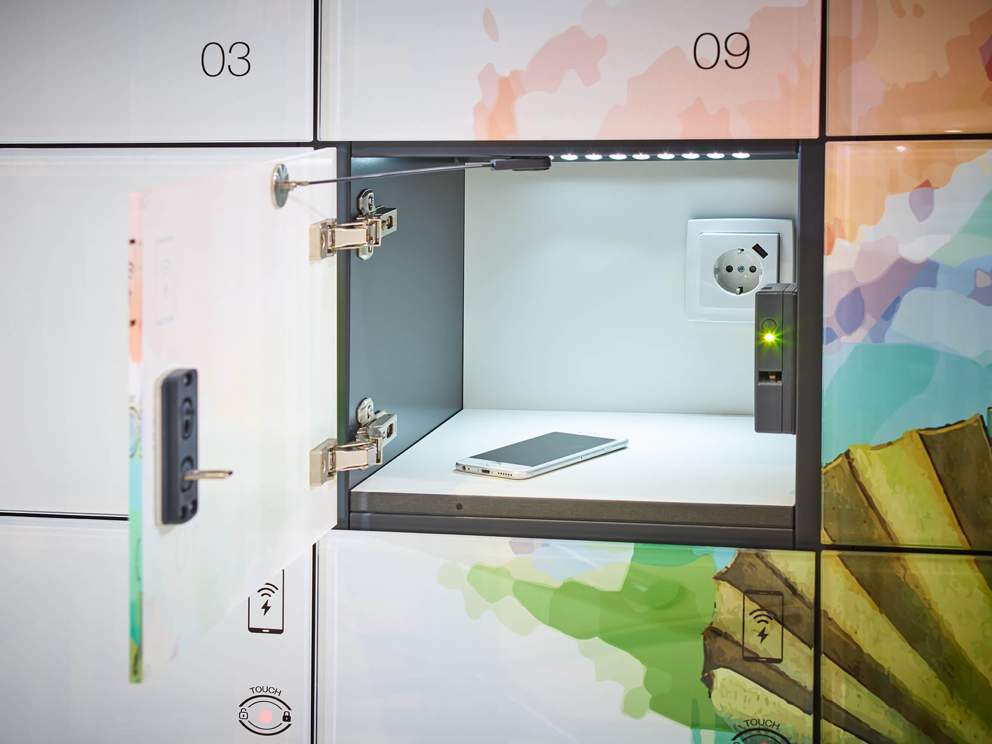 Schließfach offen, Smartphone innen, Steckdose leuchtet grün.
