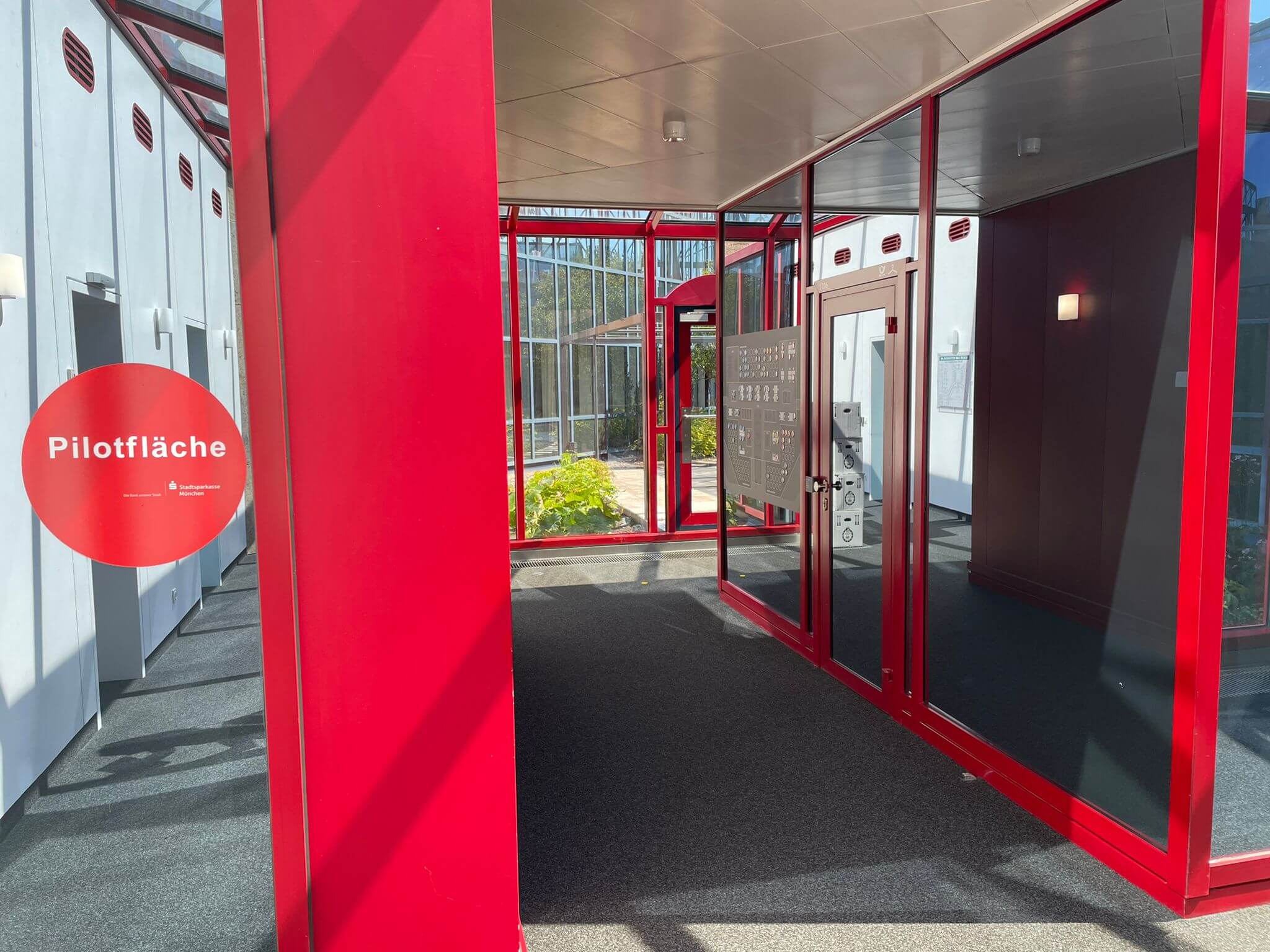 Roter Eingang mit Fensterfront, Beschilderung "Pilotfläche".