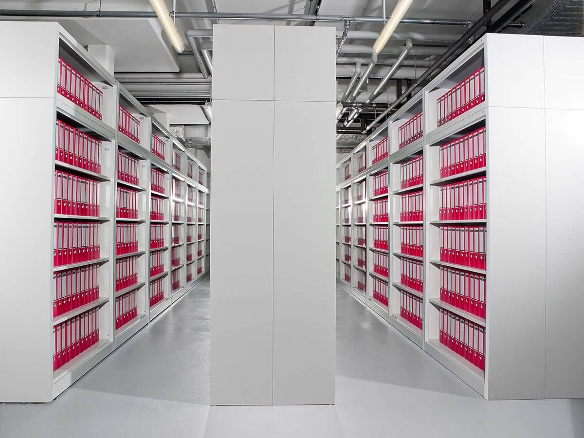 Regale gefüllt mit roten Ordnern in einem modernen Archivraum.