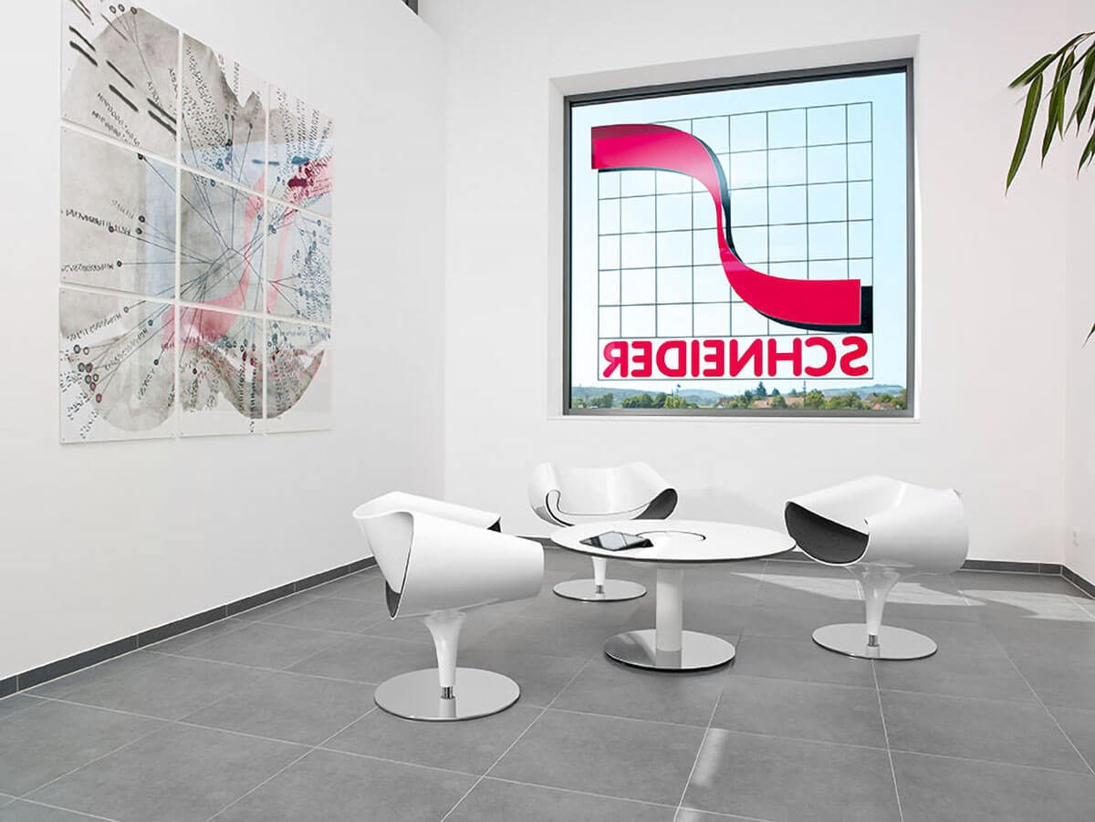 Heller Besprechungsbereich mit weißen Stühlen um runden Tisch bei SCHNEIDER.