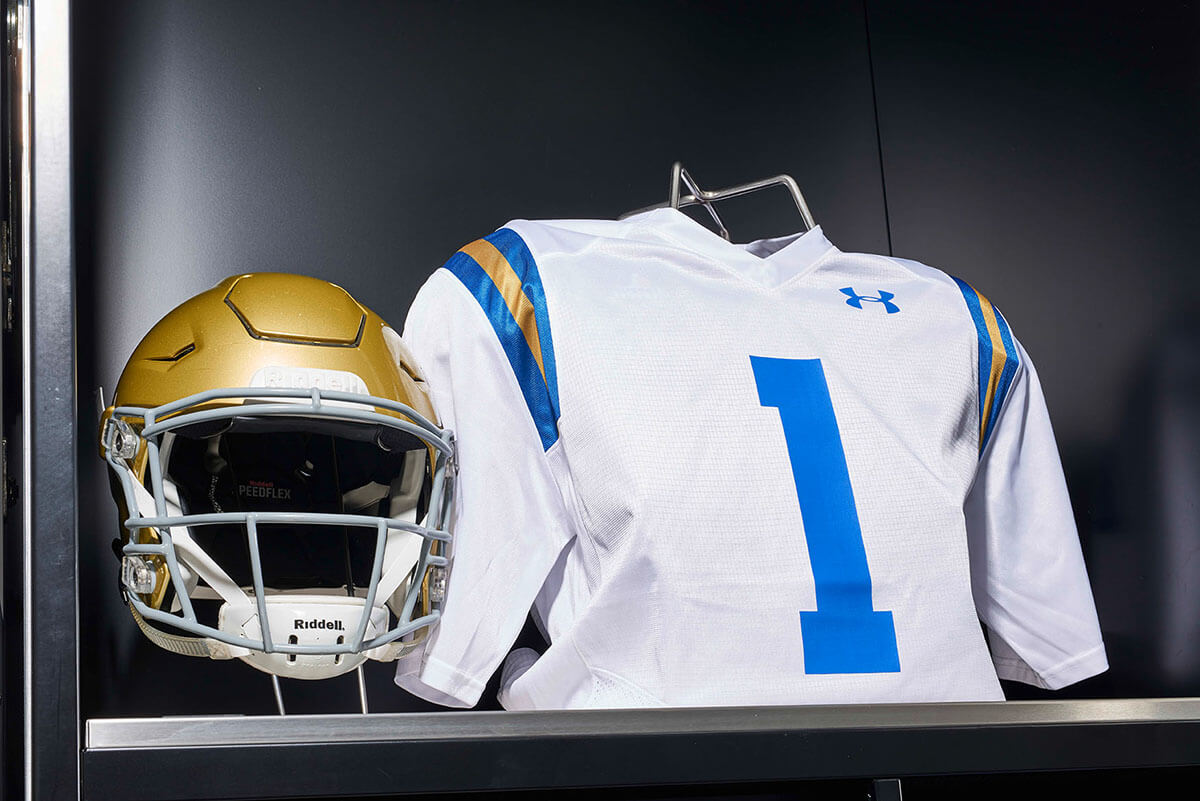 Goldener Footballhelm und weiß-blaues Trikot mit Nummer 1 in einem Schrank.