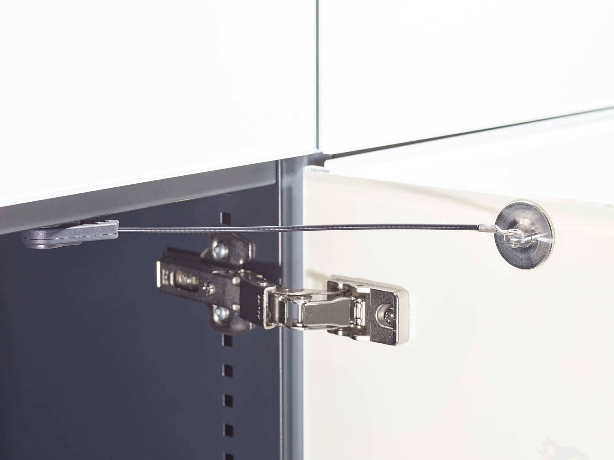 Schranktür mit Scharnier und Sicherungskabel aus Innenraumansicht.