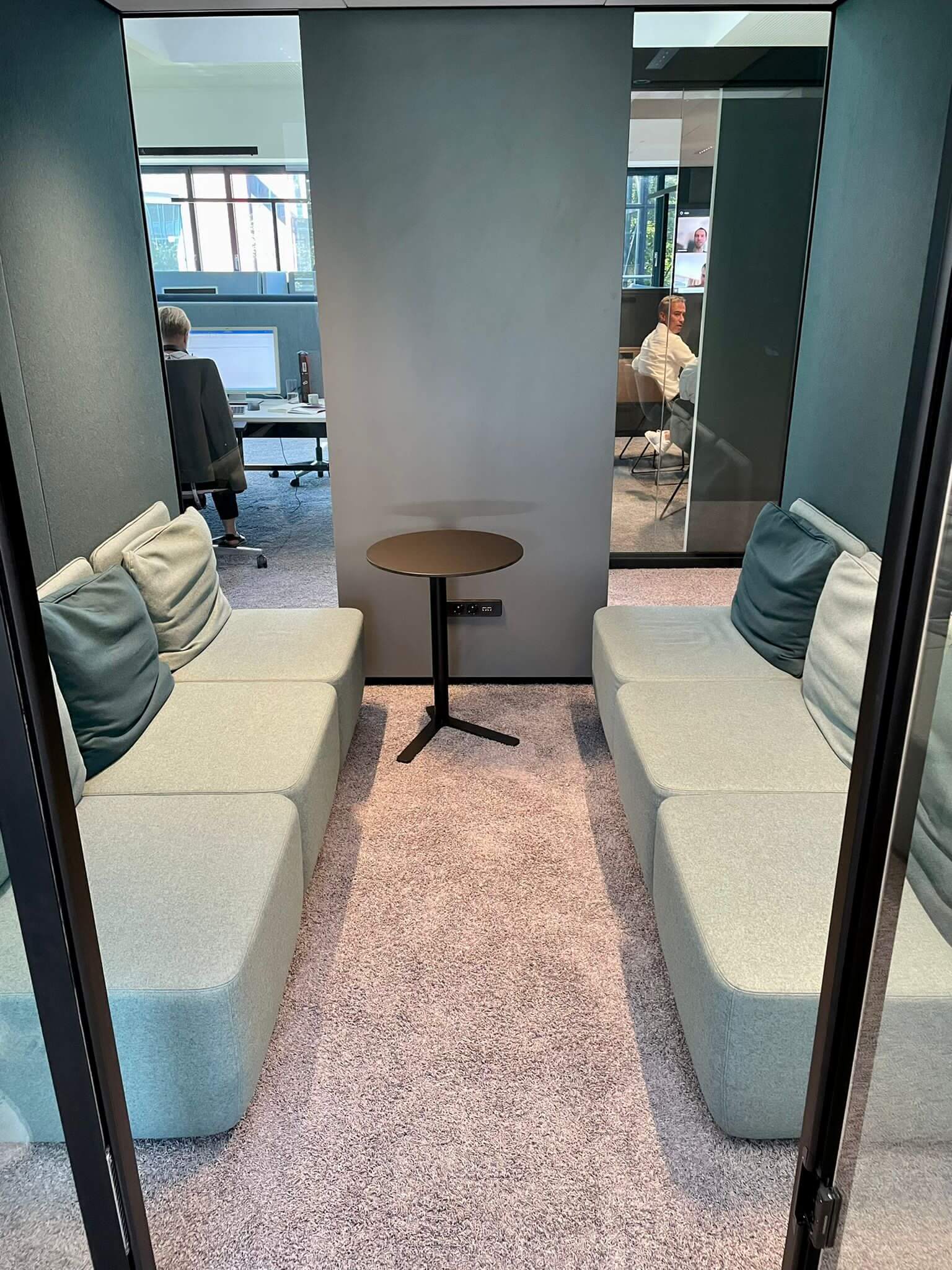 Couchbereich mit kleinem Tisch im modernen Büro mit Glaswänden.